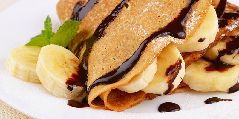 Close-up of crepes with banana and chocolate sauce